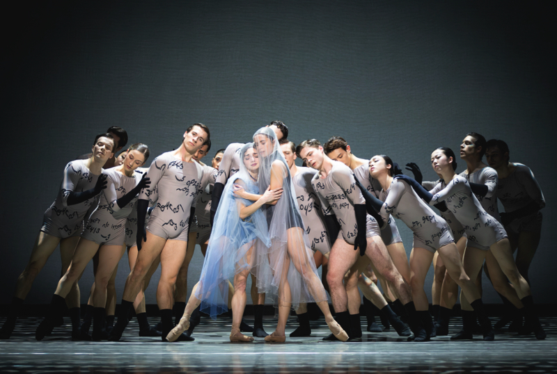 Two veiled women stand surrounded by an ensemble in grey leotards printed with the cypher of Gentleman Jack's cypher