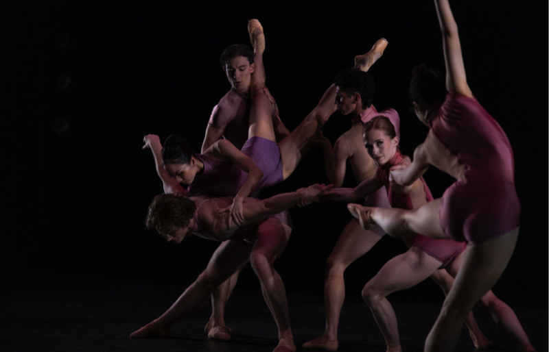 Tulsa Ballet in Divenire.  A group of dancers in shimmering leotards in tones of pink and purple form a tableau with limbs in various positions