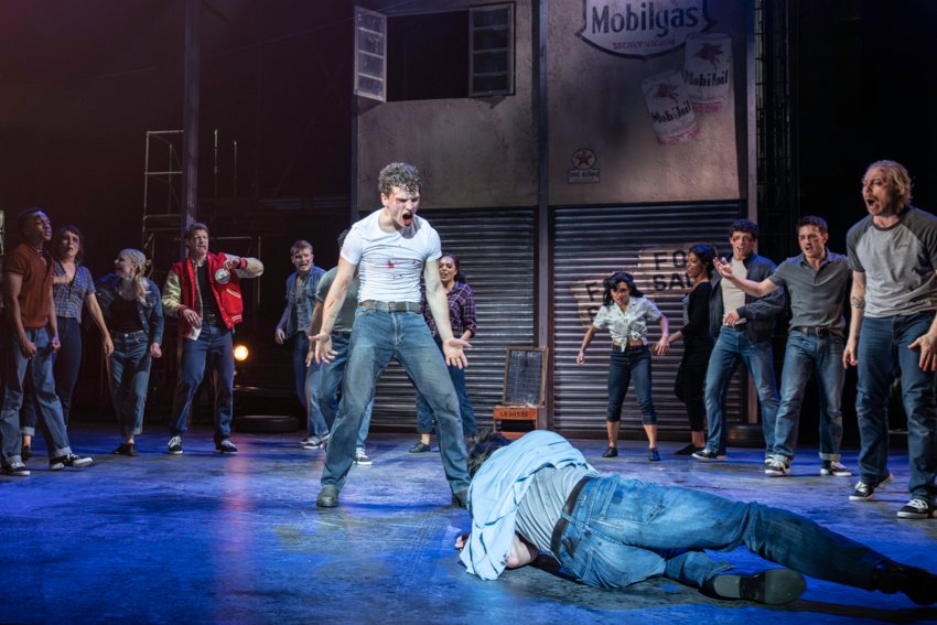 The Car Man One man in jeans and blood-stained withe T-shirt challenges another who lies on the ground. They are fighting amid a semi-circle of watchers